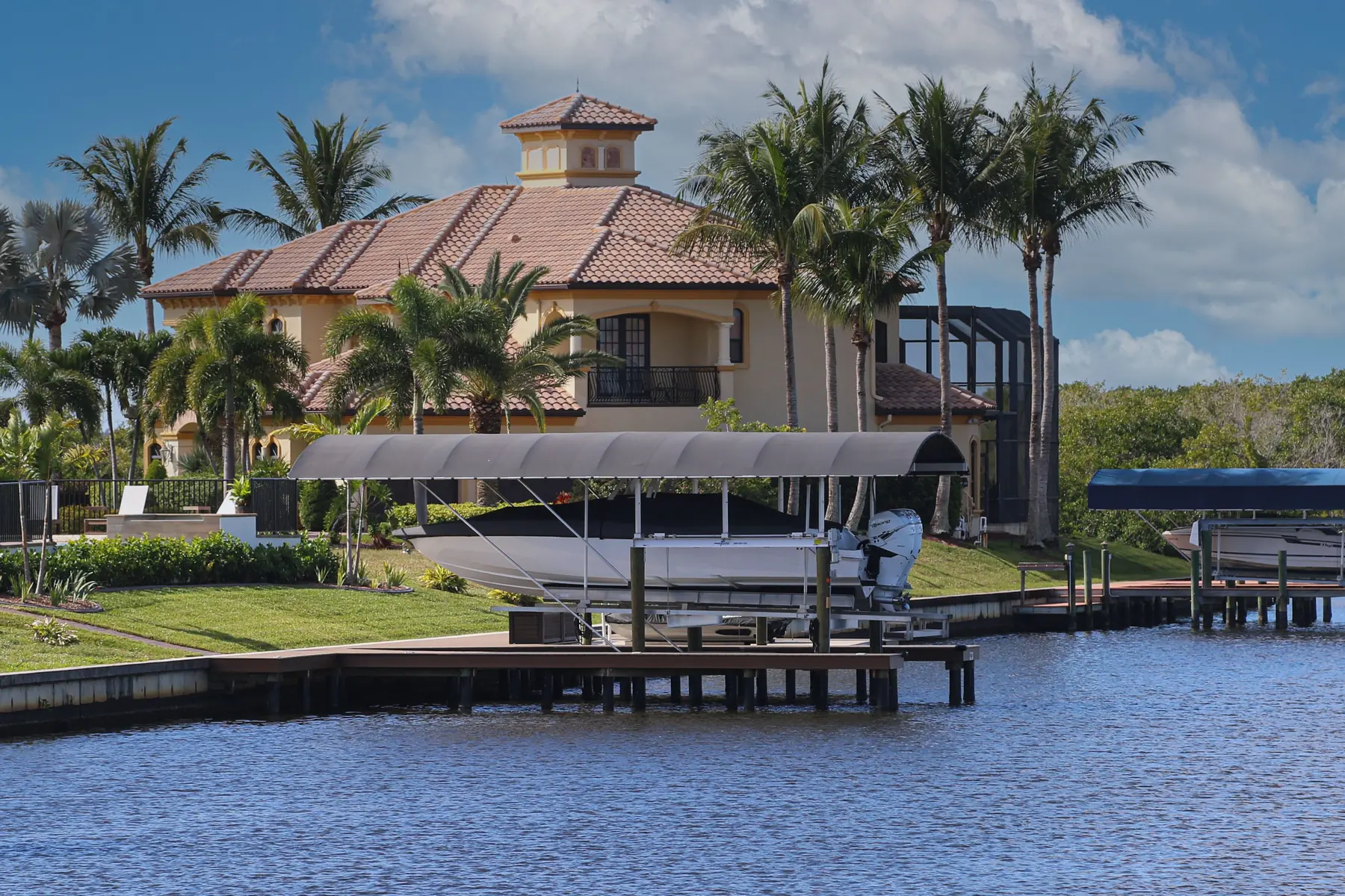 Cape Coral waterfront home with a covered boat lift on the canal behind it