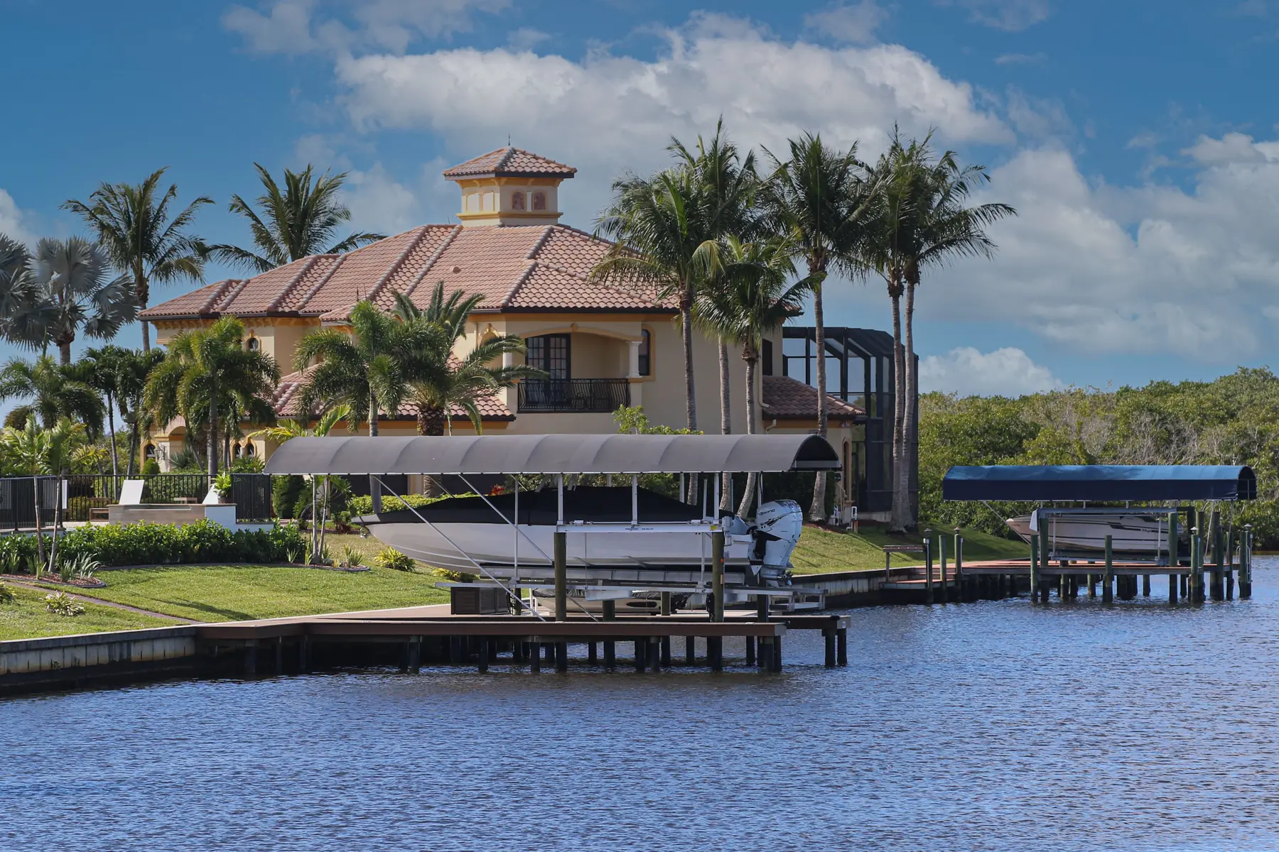 Cape Coral waterfront home with a covered boat lift on the canal behind it