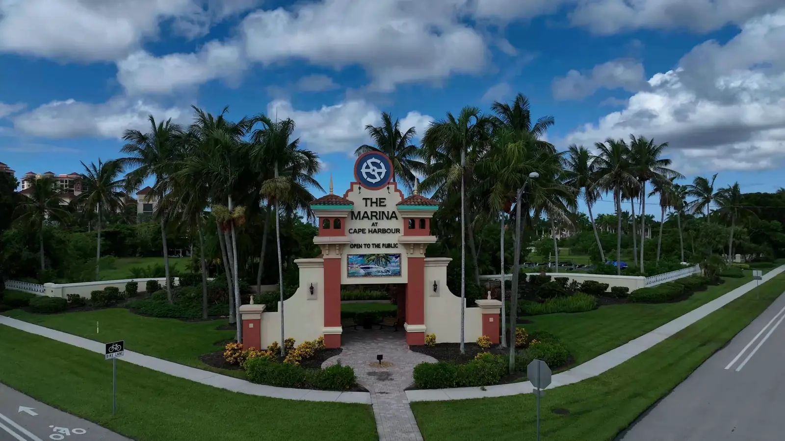 The Marina at Cape Harbour entrance archway, Cape Coral, with palms and waterfront condominiums behind