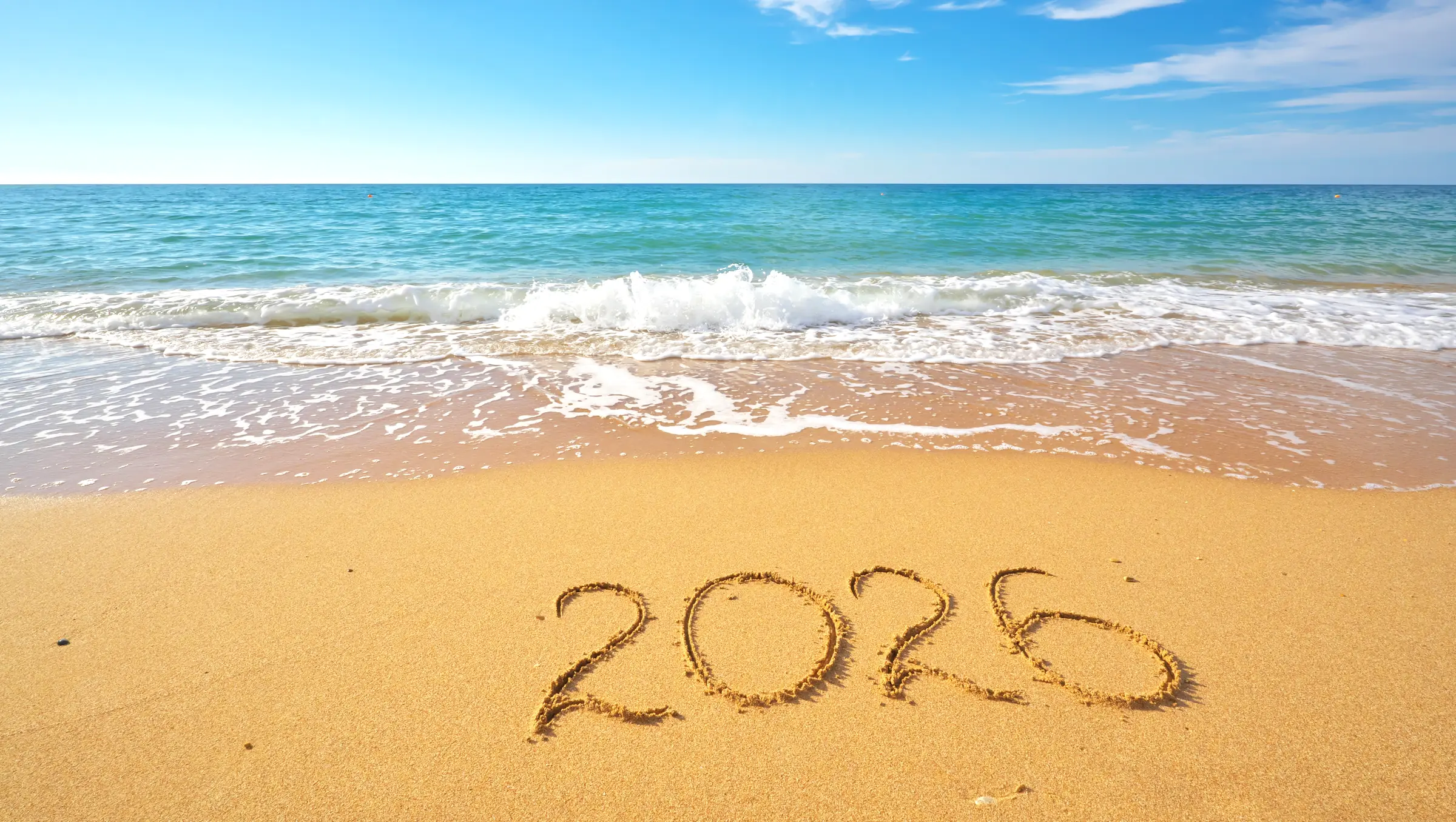 The year 2026 written in wet sand at the water's edge