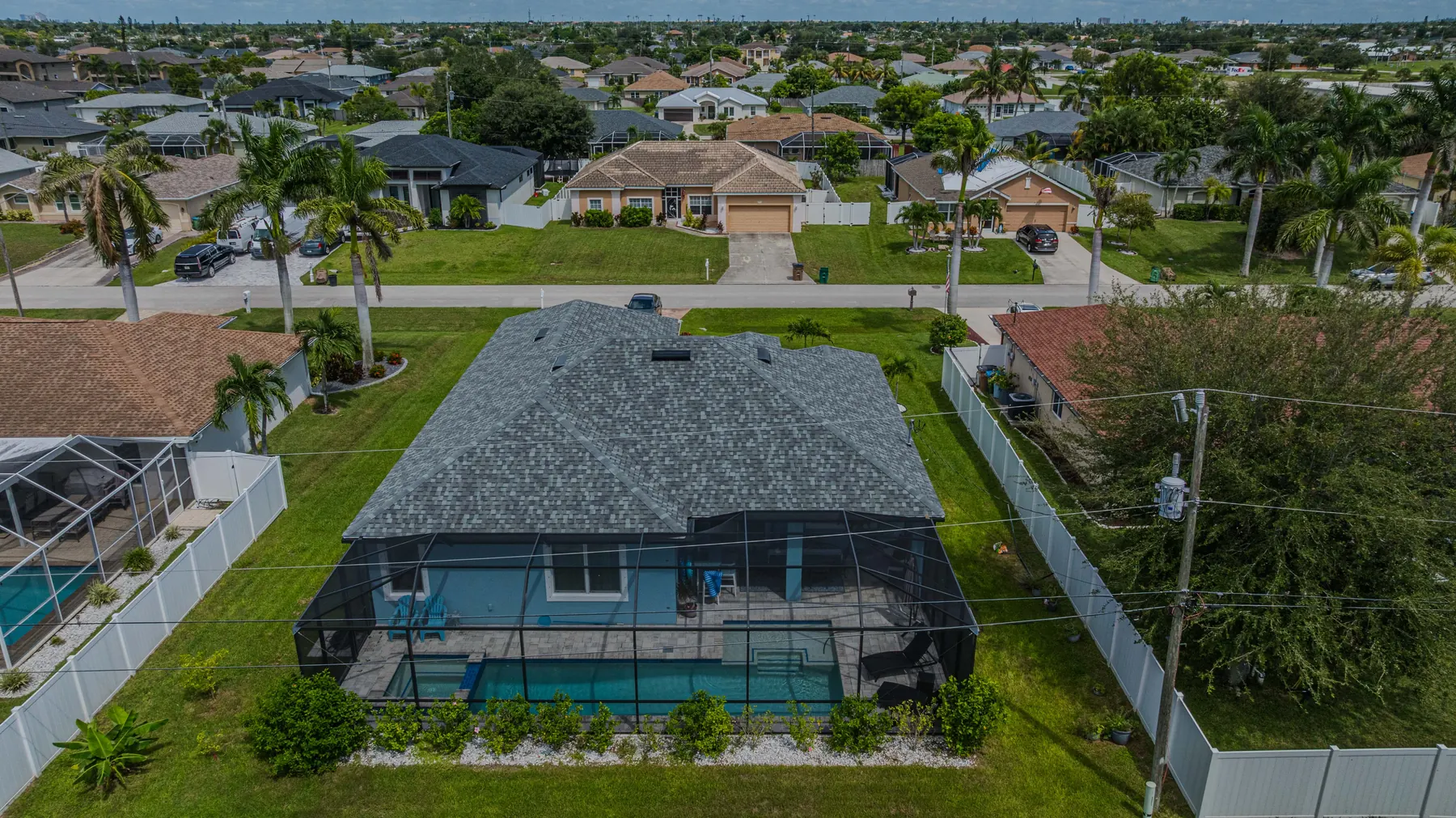 Aerial view of the back of the home, the screened pool and the fenced yard