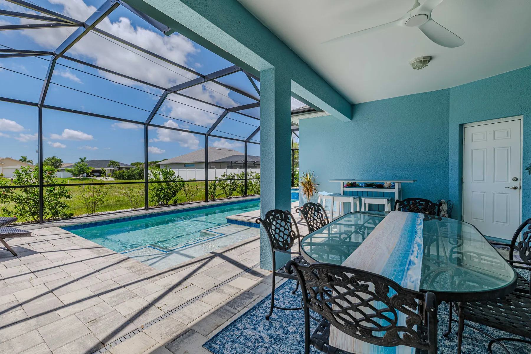Covered lanai with outdoor dining beside the pool