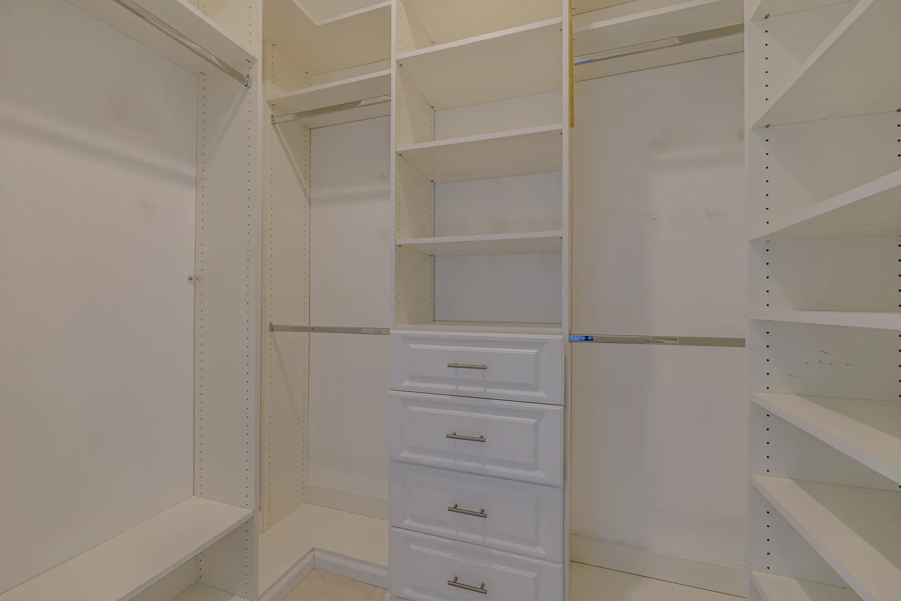 Primary closet with built-in cabinets and shelving
