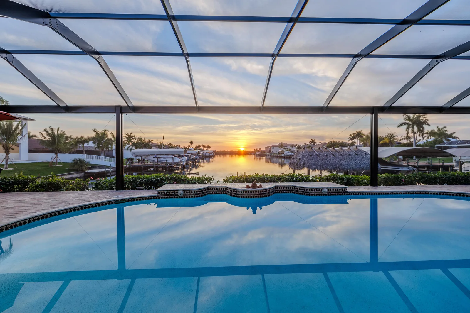 Screened lanai pool at sunset looking down a Cape Coral canal